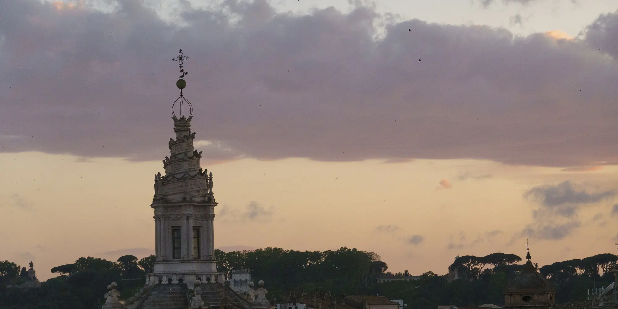Sant'Ivo alla Sapienza spiraltårnslanterne over Roms tage i den lyserøde og ravfarvede aftenbelysning.